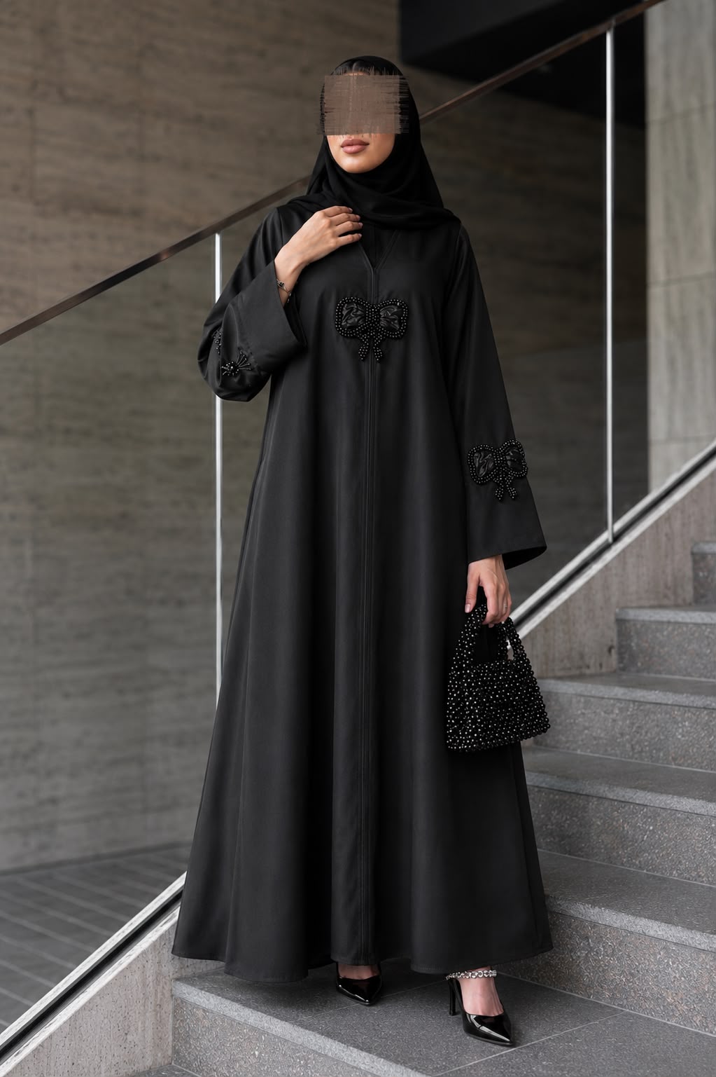 Layl Bow Abaya in black with beaded bow details on a staircase